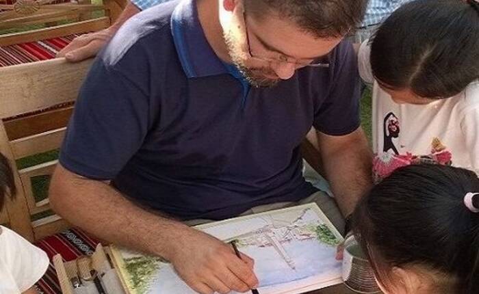 Andrea Longhi disegna circondato da alcuni bambini