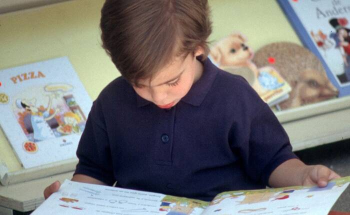 bambino che legge seduto in biblioteca