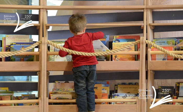 Bambino che prende un libro dagli scaffali dell'arca della zona bambini
