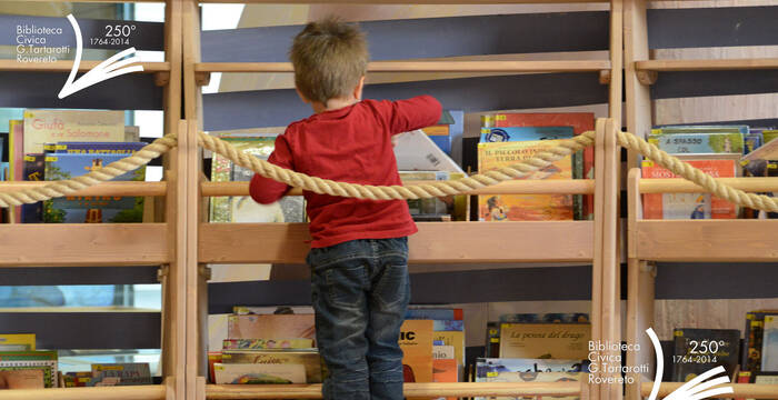 Bambino che prende un libro dagli scaffali dell'arca della zona bambini