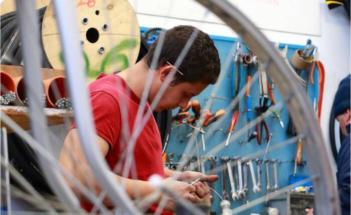fotografia che ritrae ragazzo che ripara una bicicletta (foto Silvano Brun)