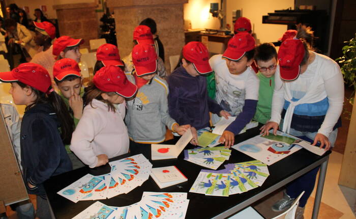 Grupppo di bambini davanti a vari volantini di progetti speciali, nel Laboratorio Arte Grafica (2013)