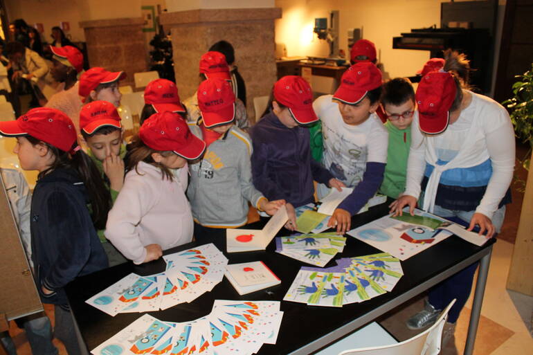 Grupppo di bambini davanti a vari volantini di progetti speciali, nel Laboratorio Arte Grafica (2013)